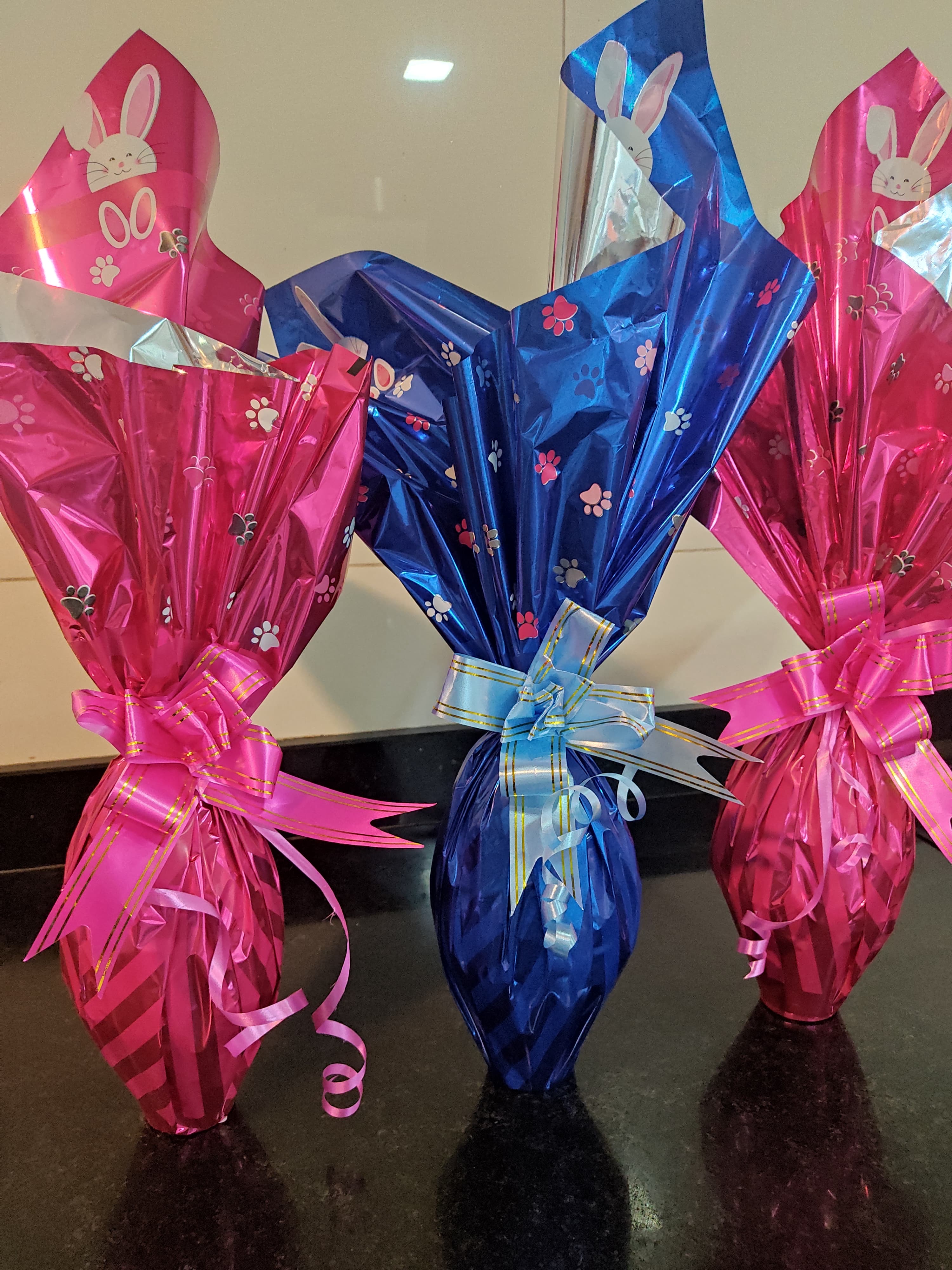 Ovos embalados em papel rosa e azul com decoração de coelhinho